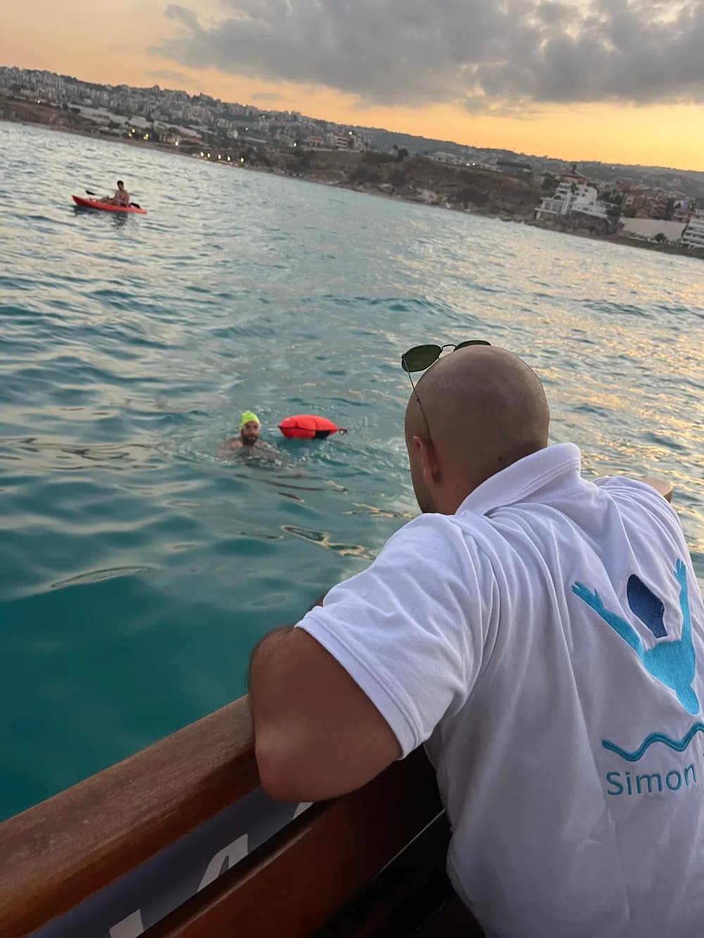 Coach watching open-water swimmers from a support boat